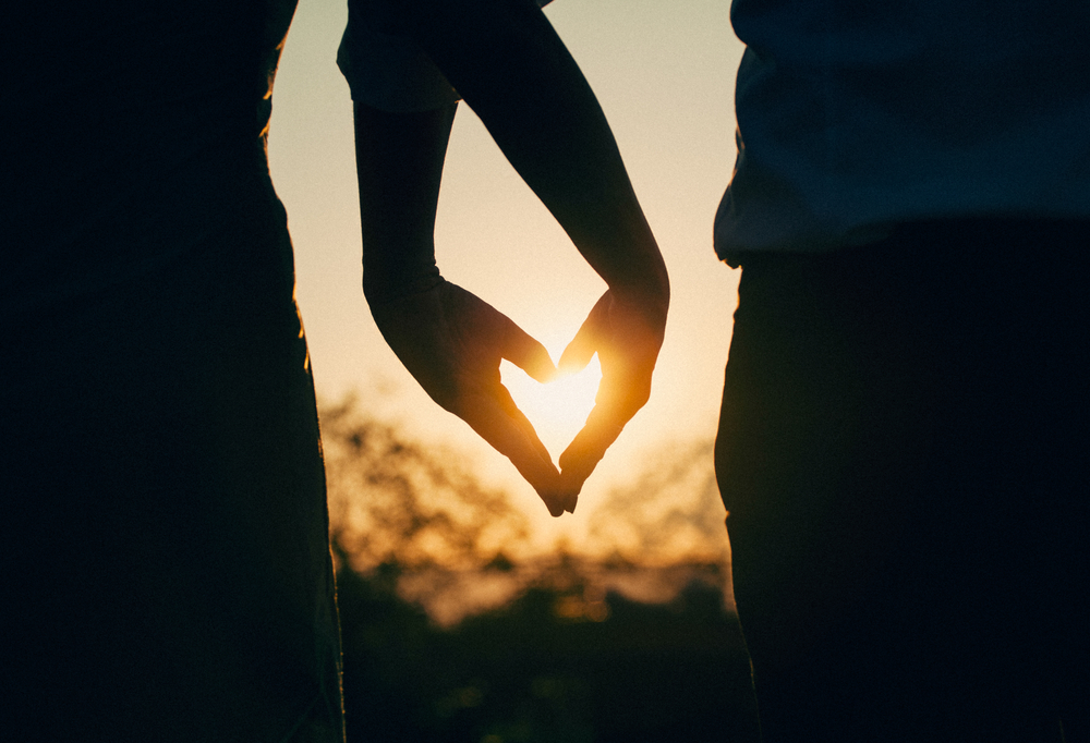 Silhouette of couple holding hands in a heart shape